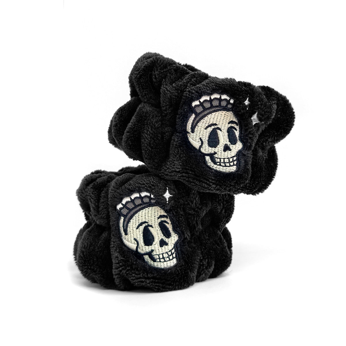 A pair of black plush hooded bath towels featuring embroidered white and gray skulls with small star accents, displayed on a clean white background.